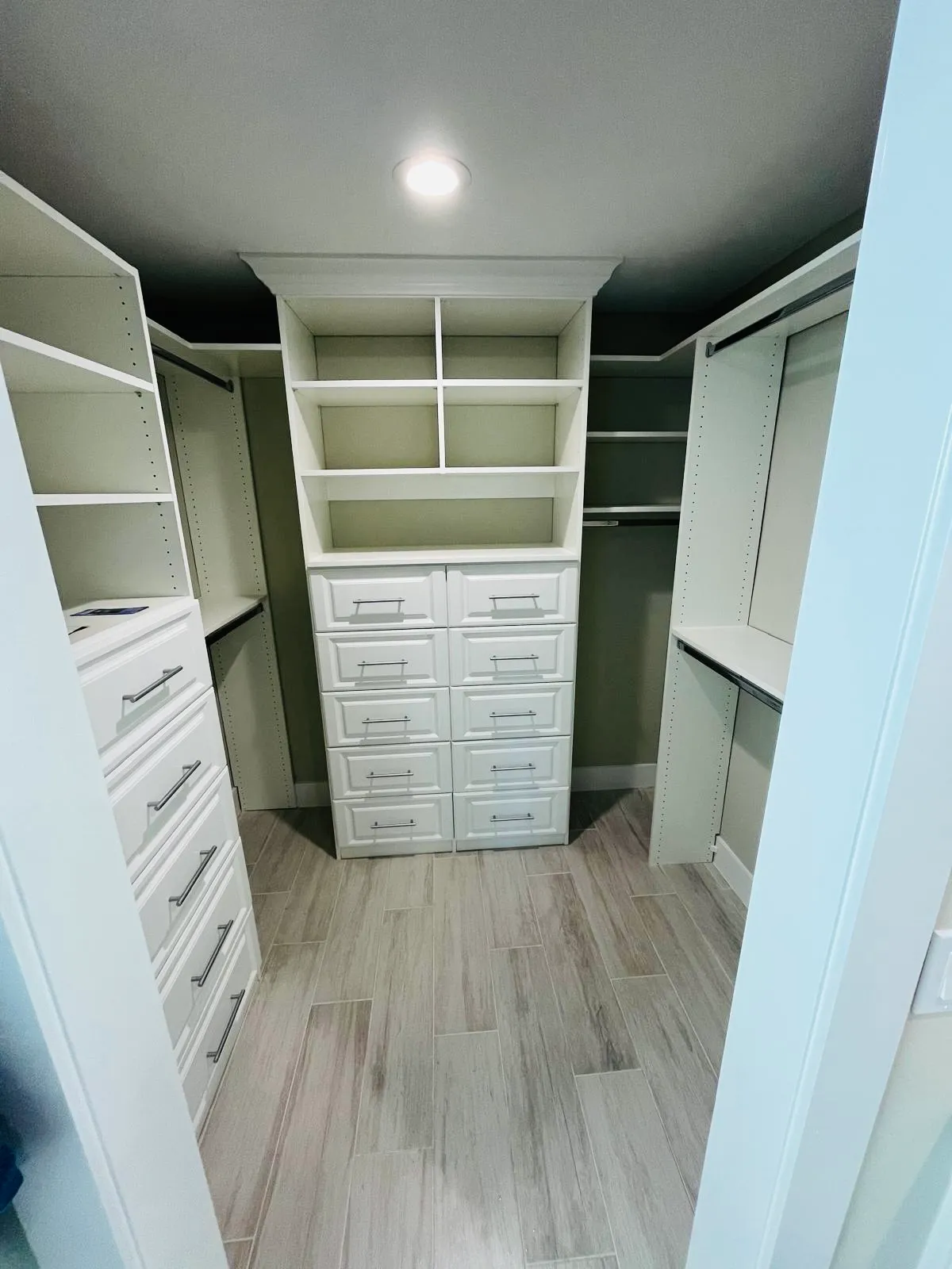 Walk-in closet with a custom drawer organizer tower and upper cubbies in Venice, FL