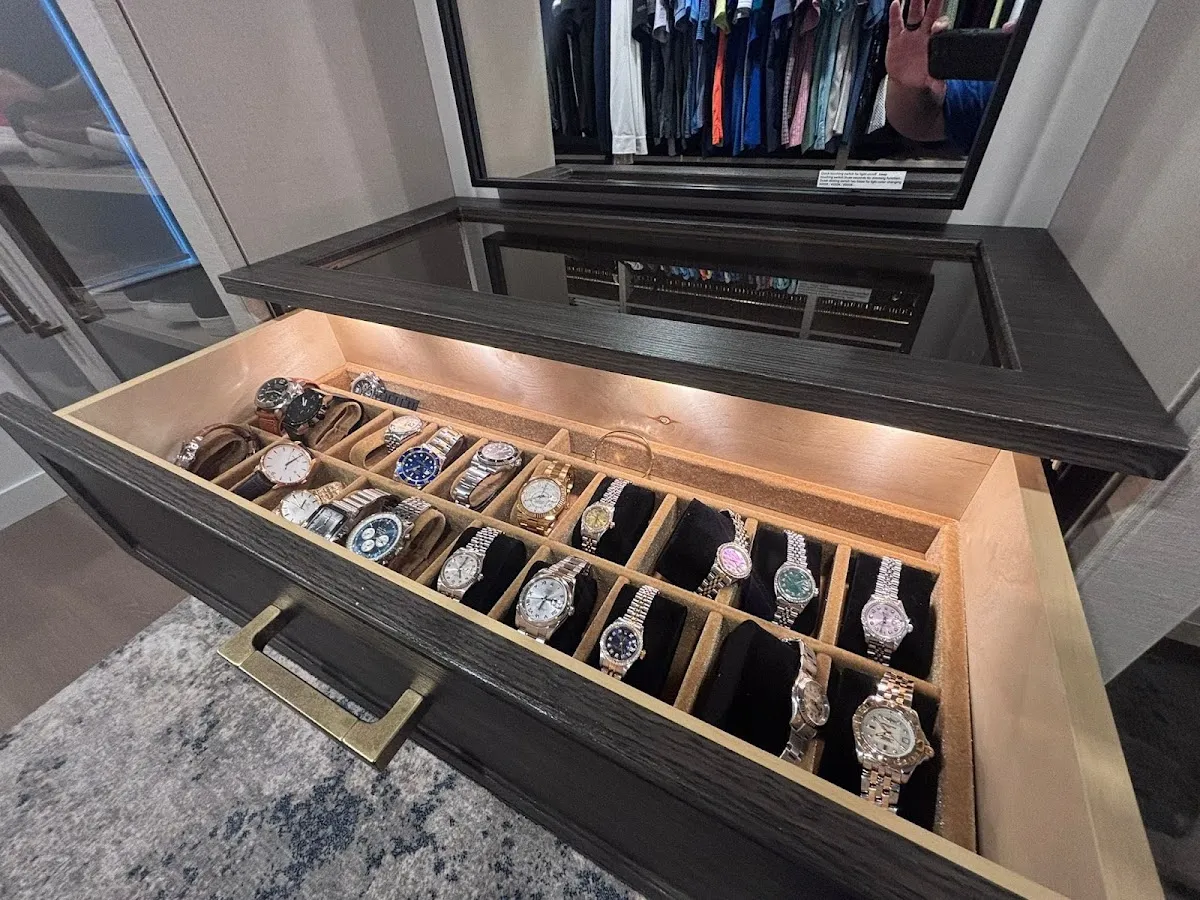 Glass-topped watch drawer with velvet-lined dividers and a brass pull inside a custom closet in Sarasota, FL