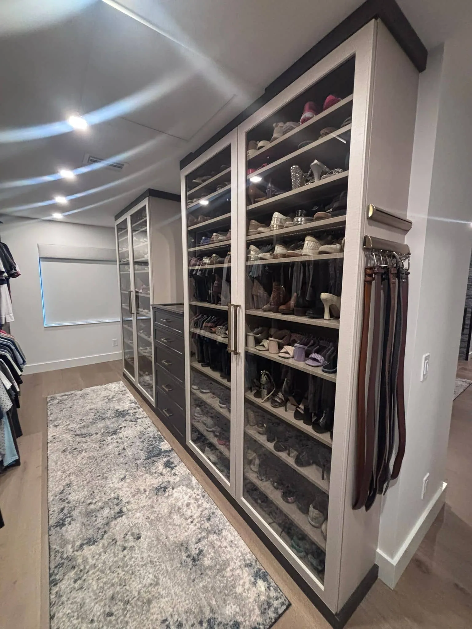 Custom wardrobe closet with backlit glass-front shoe display cabinets and integrated belt storage in Bradenton, FL