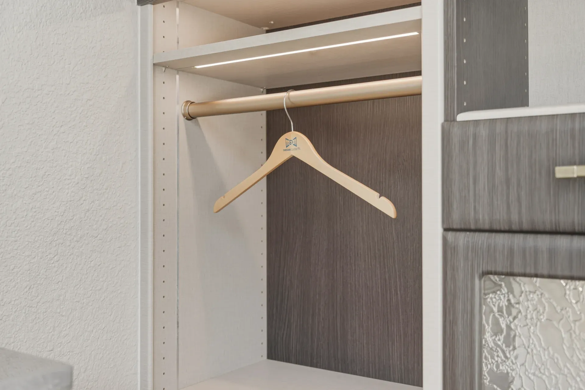 LED-lit closet hanging rod detail with a branded wooden hanger in the Bradenton showroom