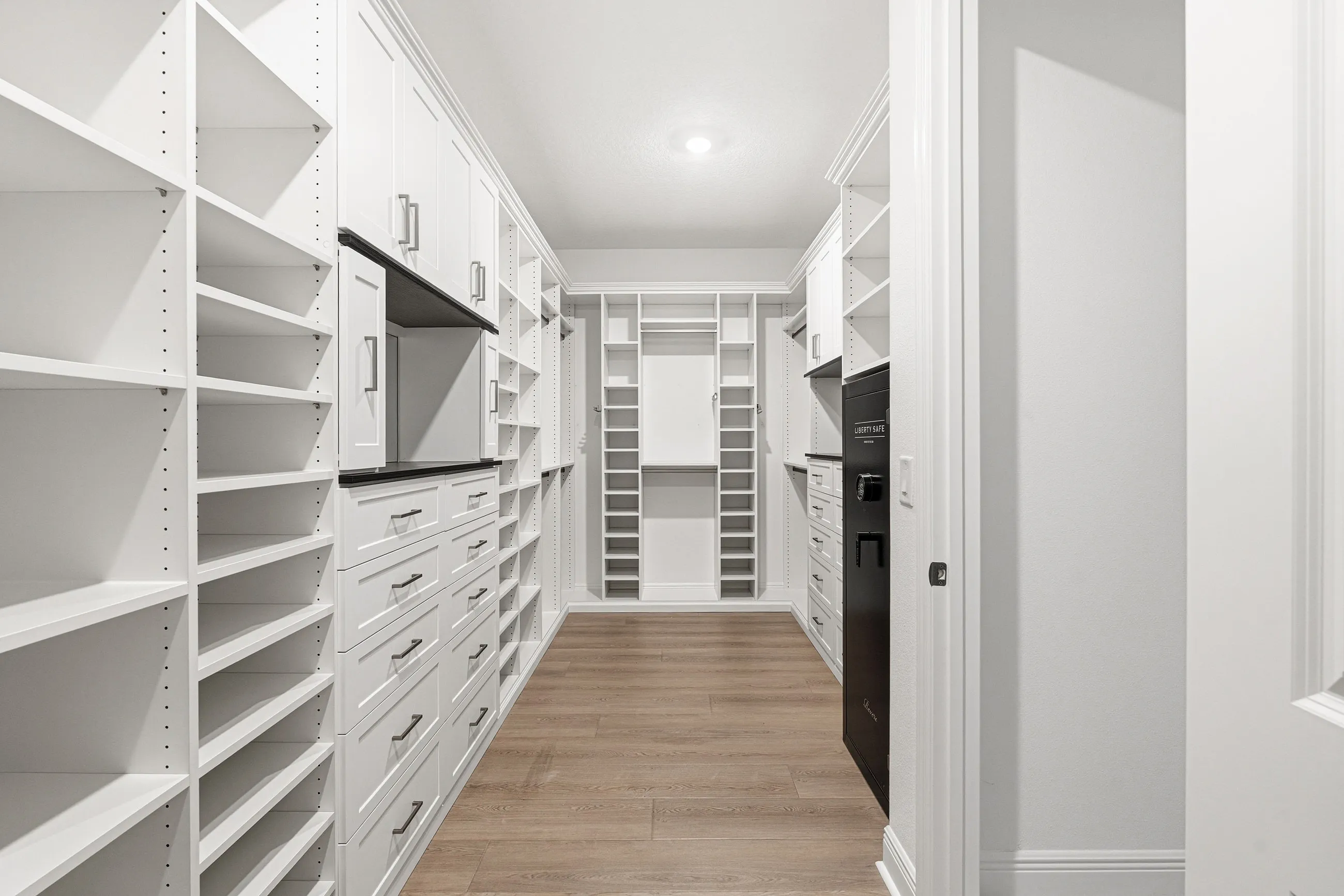 Custom walk-in closet with full-length dual-wall shelving and drawer banks installed in Bradenton, FL