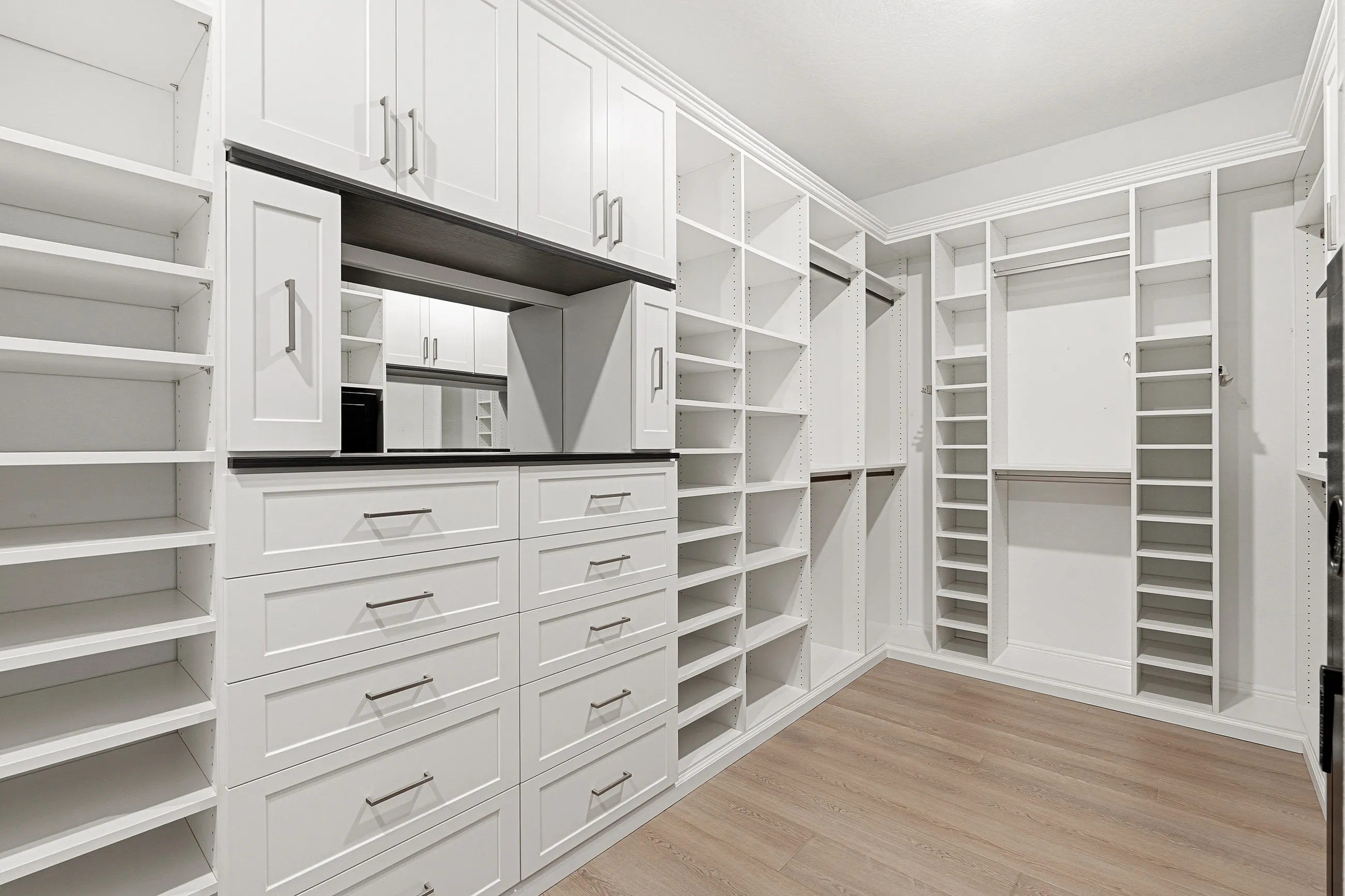 Luxury walk-in closet with upper cabinets, vanity mirror and floor-to-ceiling shoe shelving in Bradenton, FL