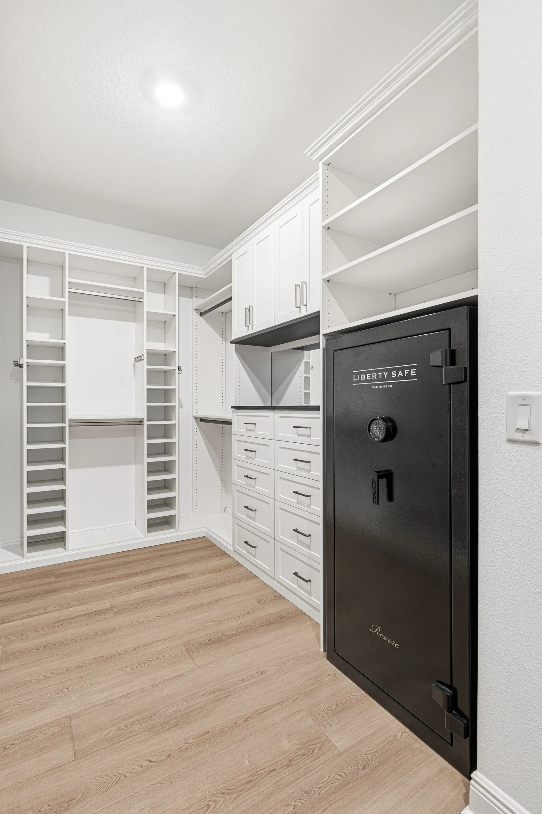Custom walk-in closet with a built-in safe integrated into white cabinetry in Bradenton, FL